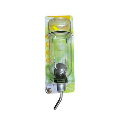 A clear plastic bird waterer bottle with a metal spout and a small clear feeder cup attached above it, shown in its green and yellow retail blister packaging on a white background.