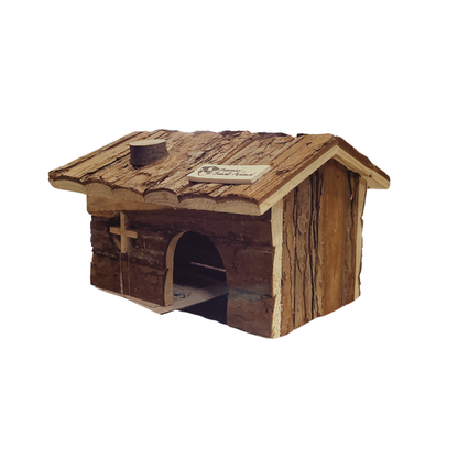 A small rustic wooden house or cabin for small animals with bark-textured roofing, an arched entrance opening to a dark interior, a small cross on the front wall, and a small plaque on the roof, shown on a plain white background.